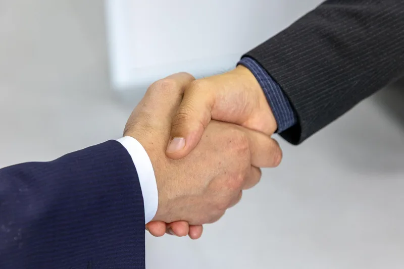 Two people in business suits shaking hands to seal an agreement