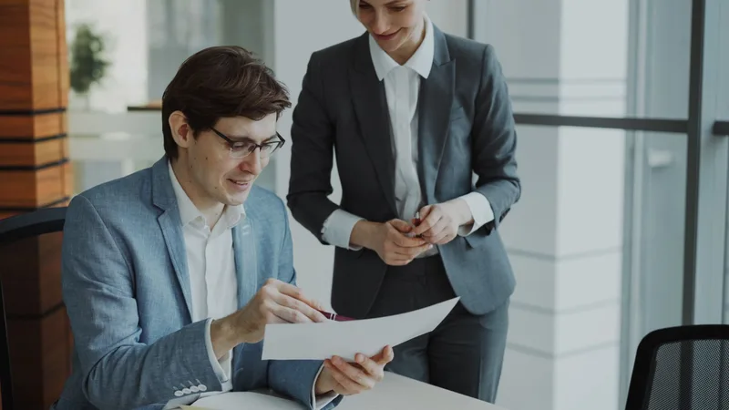 Two business colleagues reviewing a printed document together in an office