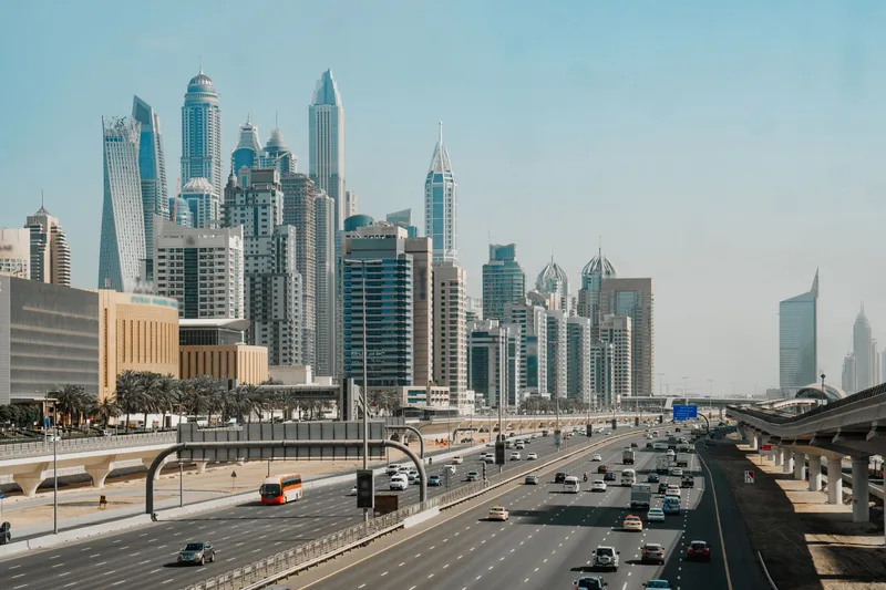 Dubai high-rise towers beside a busy multi-lane highway on a clear day