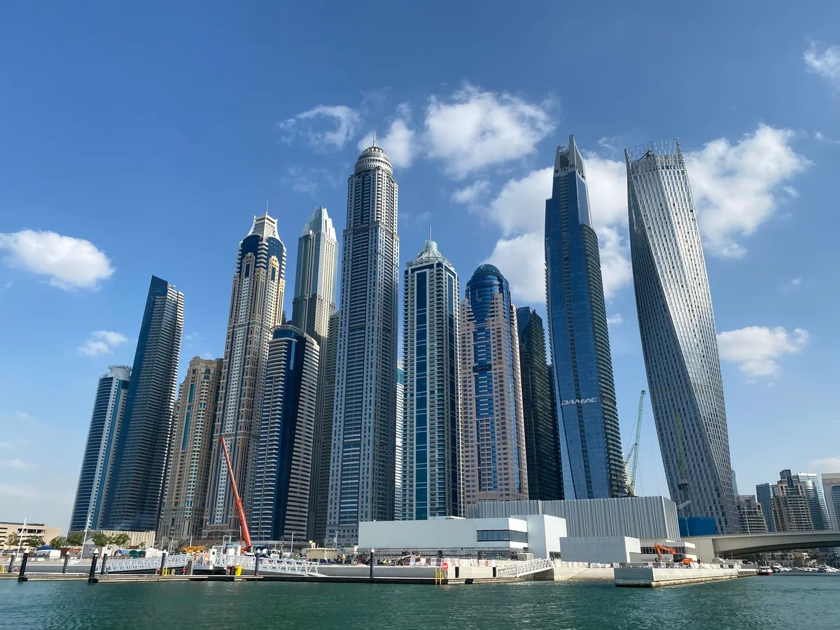 Tall residential towers in Dubai Marina rising above a waterfront under a blue sky