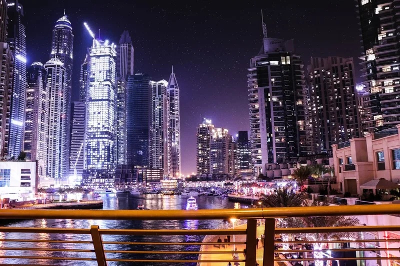 Modern banking district in Dubai with towers reflected in water — US citizens with UAE bank accounts totaling more than $10,000 at any point must file annual FBAR reports with FinCEN