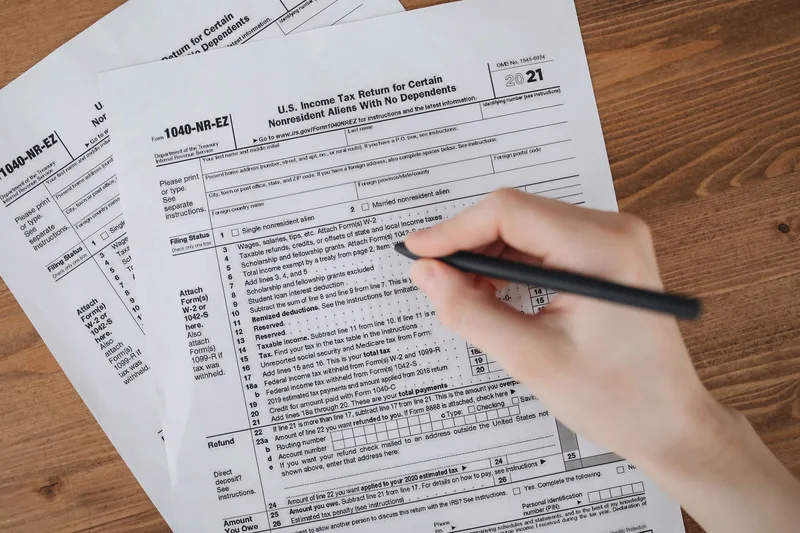 IRS Form 2555 document alongside a UAE residence visa — the Foreign Earned Income Exclusion allows qualifying US citizens in Dubai to exclude up to $130,000 of earned income from US federal taxes in 2025