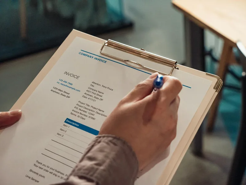 Person holding a clipboard with an invoice, representing VAT submission professional service fees